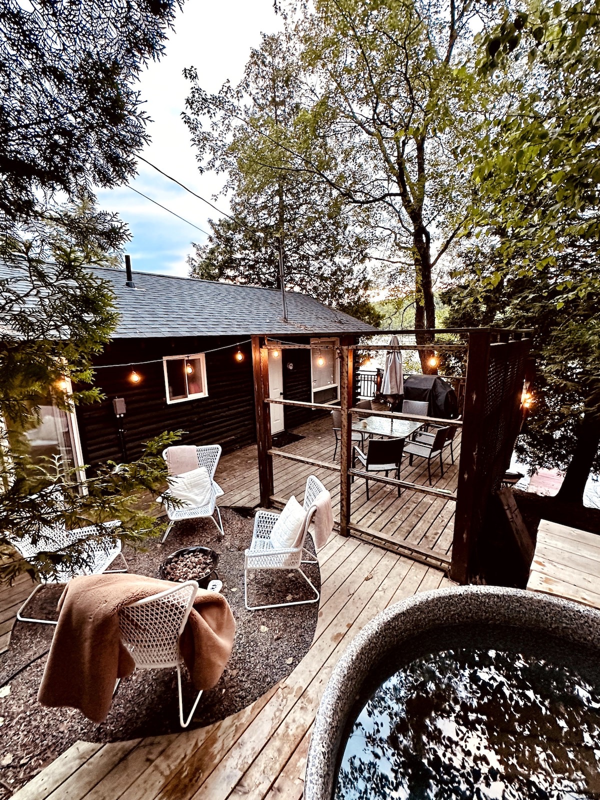 A cottage deck at dusk with string lights